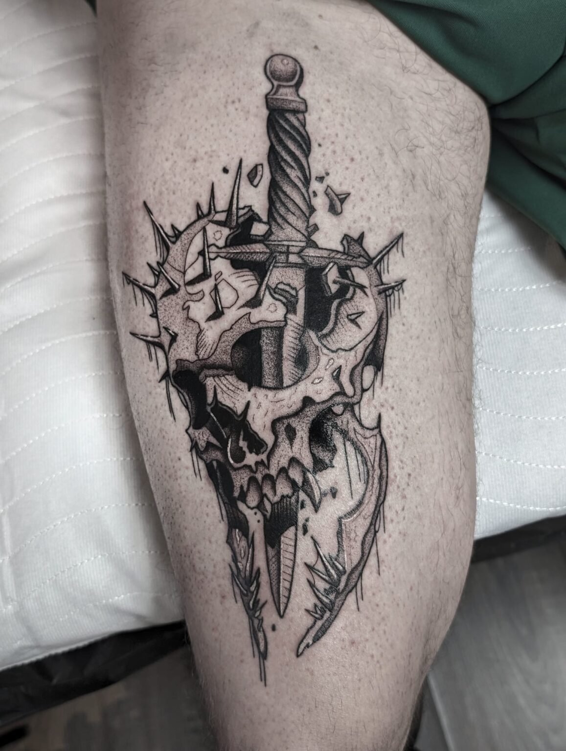 Tattoo eines Schädels, durchbohrt mit Schwert – dynamisch und detailreich. Tätowierung aus Menden, Unna, Wickede, Iserlohn, Werl.
