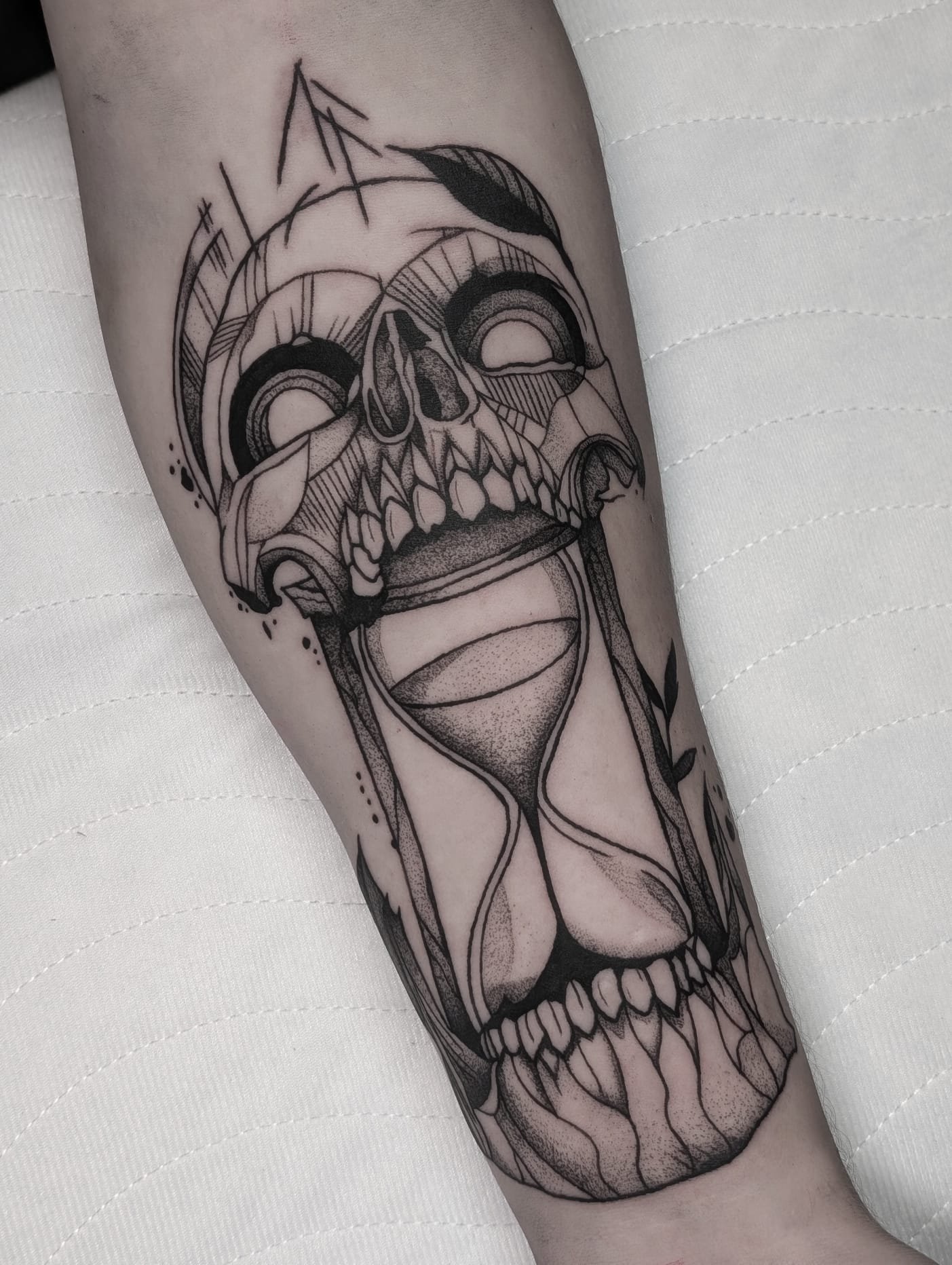Tattoo eines Schädels mit integrierter Sanduhr – Symbol für Vergänglichkeit und Zeit. Feines Blackwork Tattoo aus Menden, Unna, Wickede, Iserlohn, Werl.